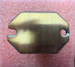 Brass-colored metal plate with a cutout on a red textured background