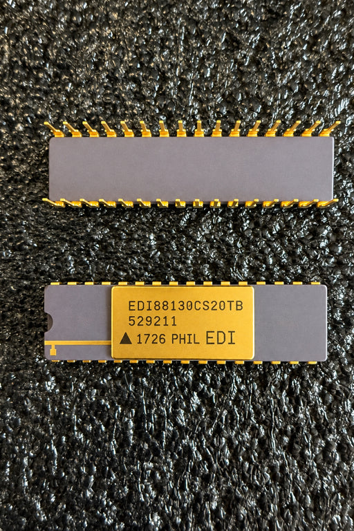 electronic components with gold-plated pins and a gold label, placed on a dark textured surface. The lower component has a gold label with black printed text including 'EDIS81130CS20TB' and 'PHIL EDI'.
